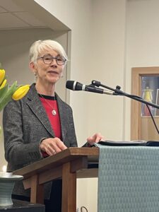 Photo of Rev. Kate Tucker speaking into a microphone