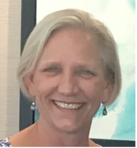 A white woman with short blonde hair smiles warmly at the camera